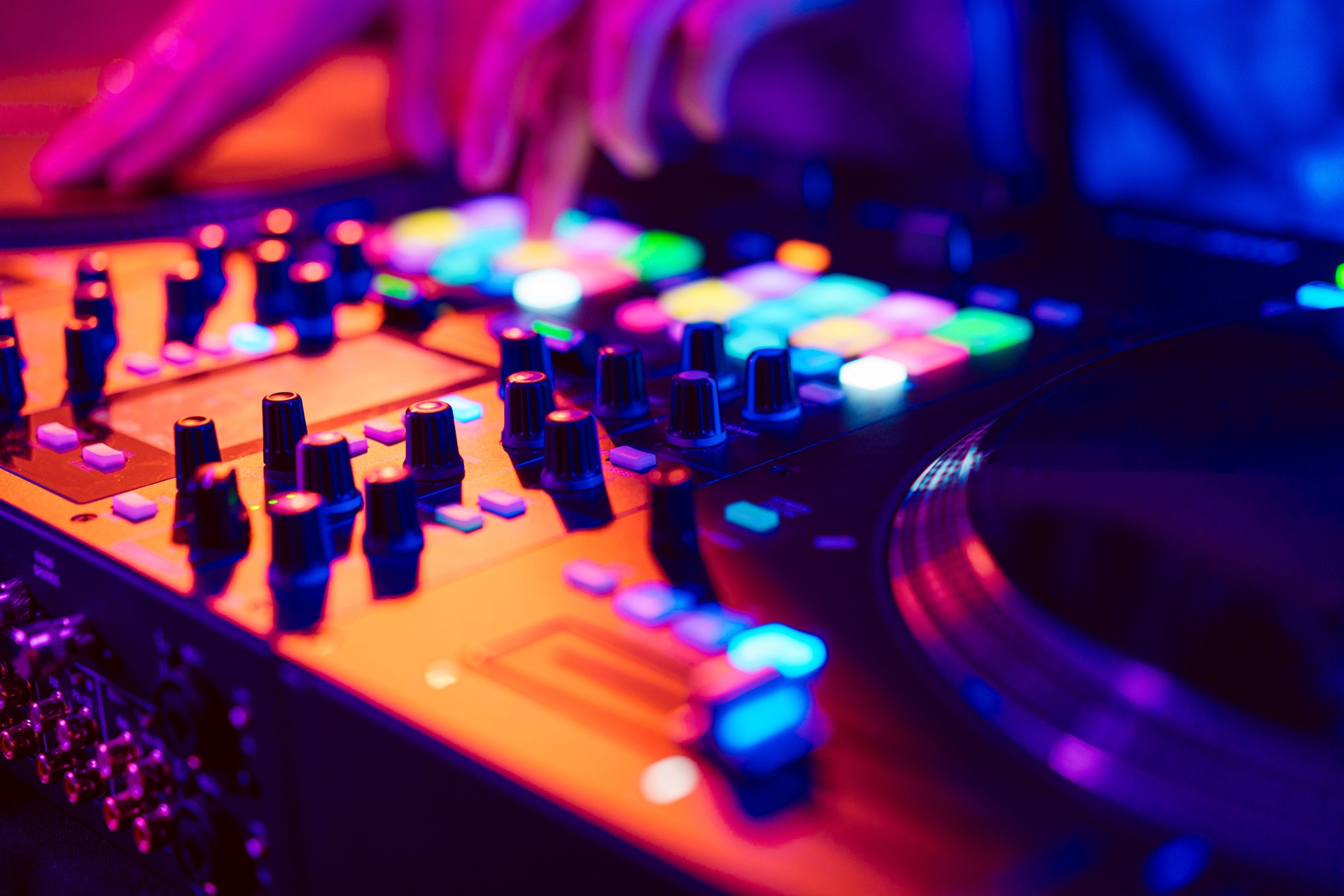 Close up of DJ hands on dj console mixer during concert in the club