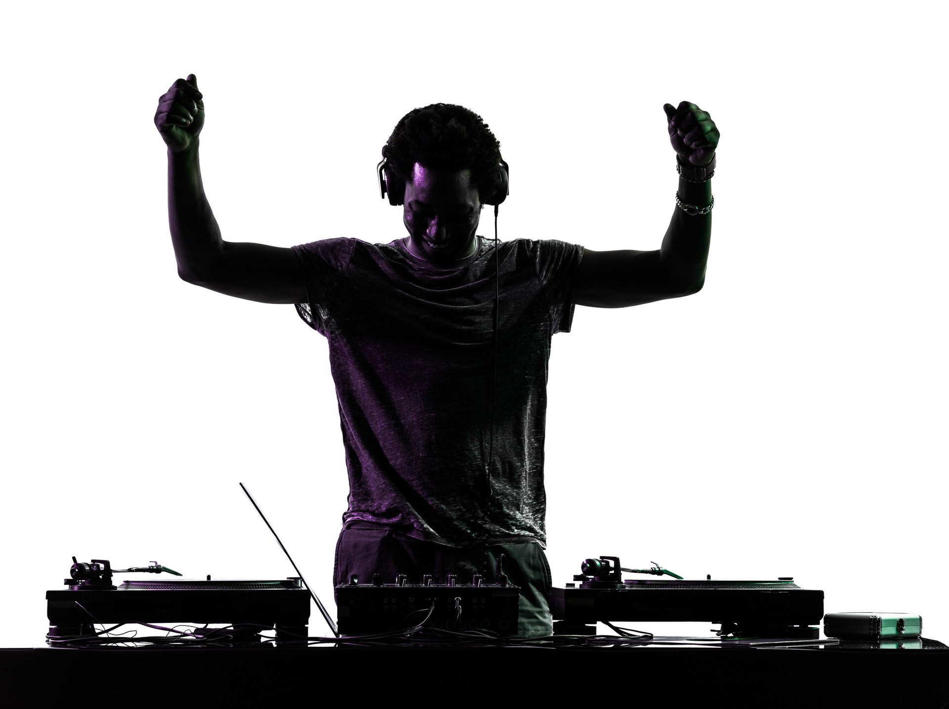 Silhouette of disc jockey raising arms over turntables